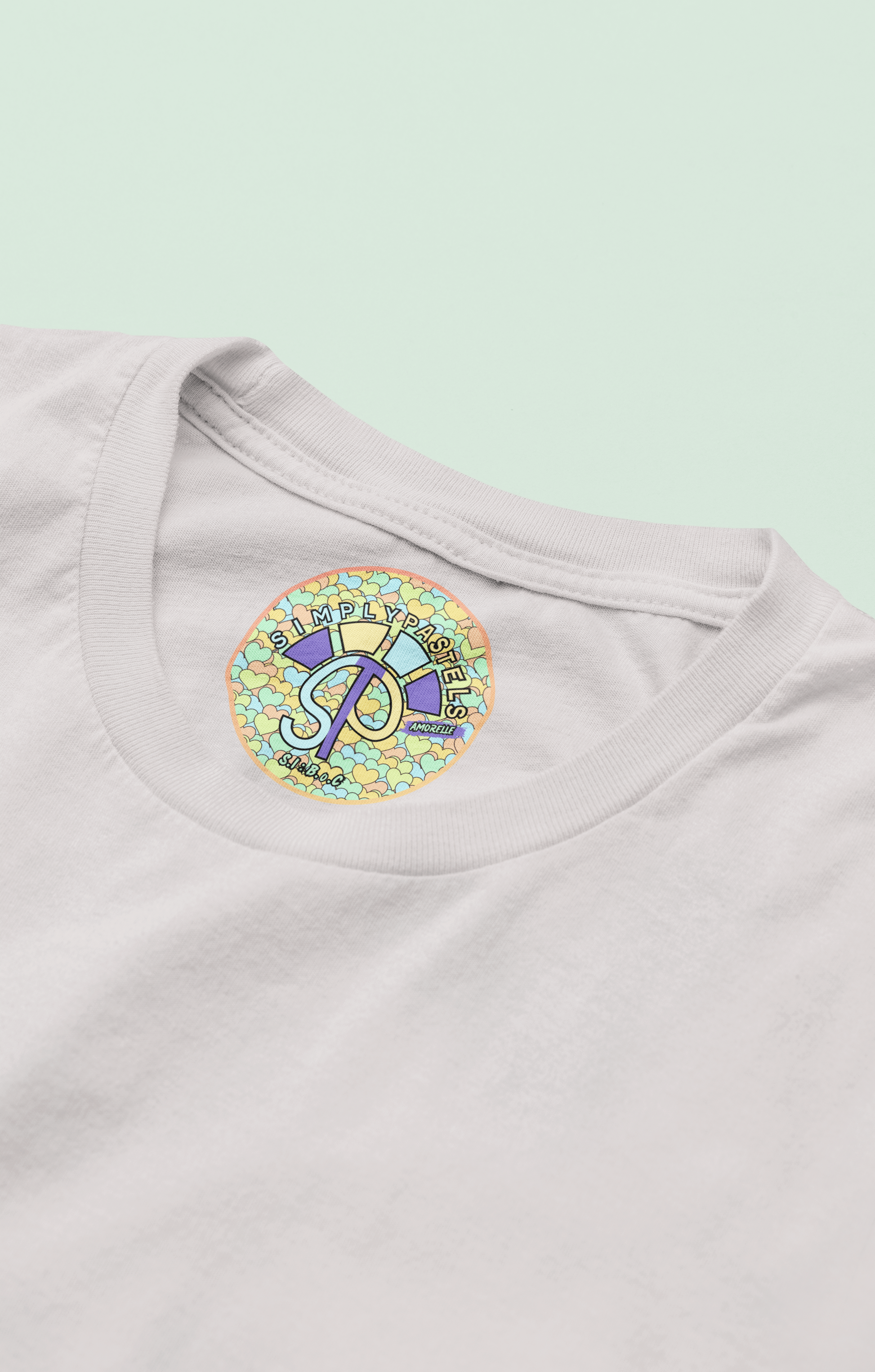 Label view of the off-white Amorelle organic cotton t-shirt with a pastel graphic design, from Simply Pastels, a UK-based premium ethical clothing brand.