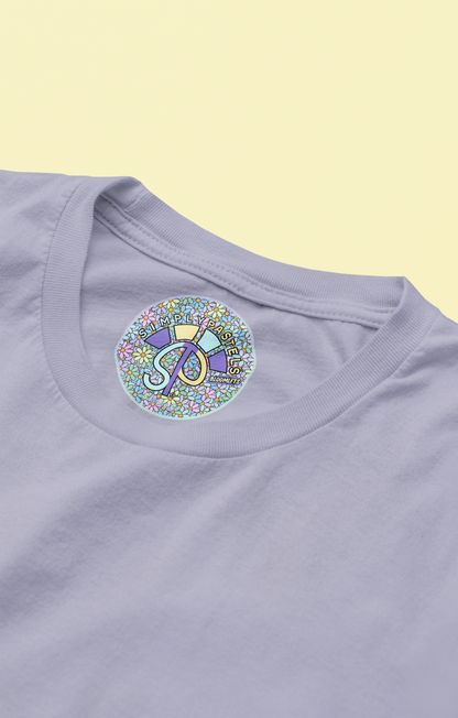 Label view of the lavender Bloomlets organic cotton t-shirt with a pastel graphic design, from Simply Pastels, a UK-based premium ethical clothing brand.