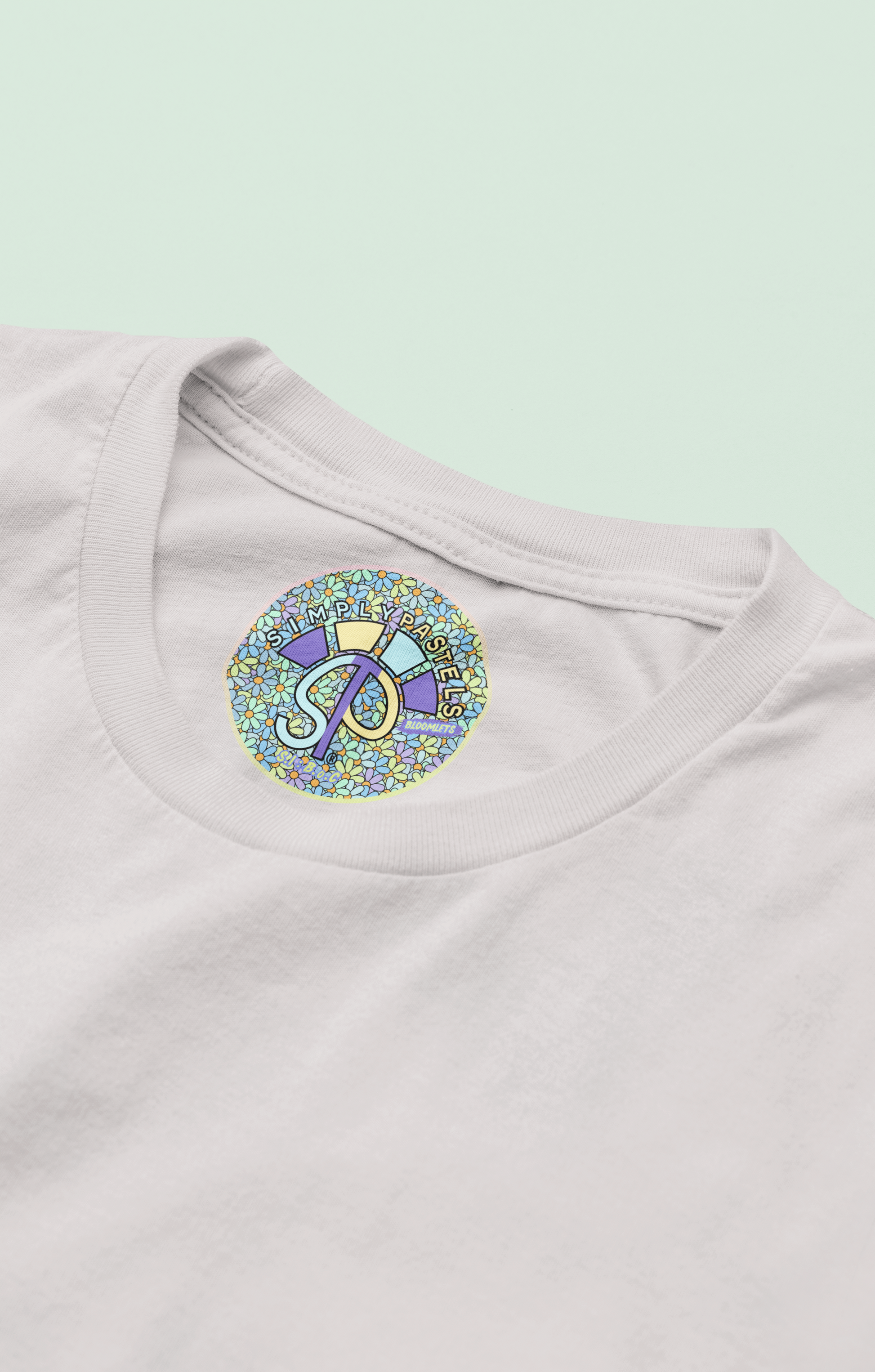 Label view of the off-white Bloomlets organic cotton t-shirt with a pastel graphic design, from Simply Pastels, a UK-based premium ethical clothing brand.
